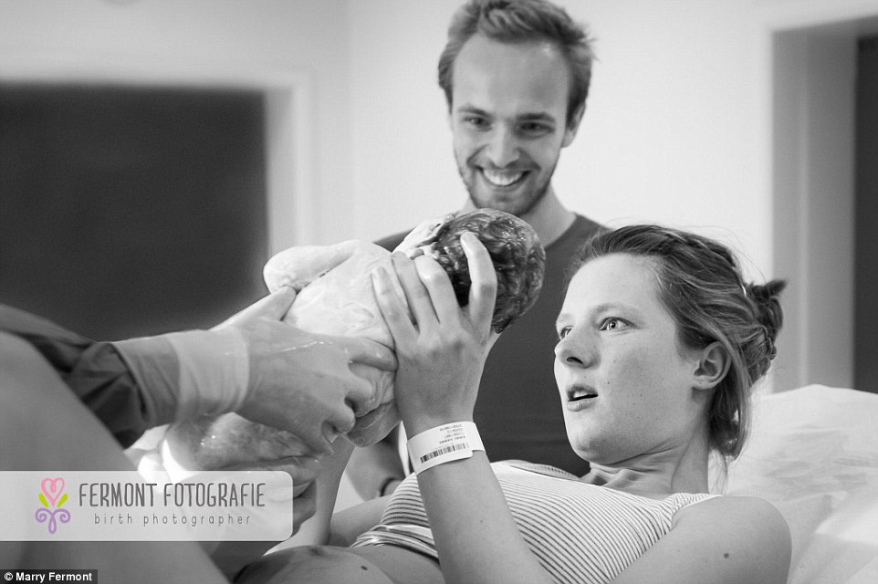 A mother looks amazed as she meets her baby for the very first time. Marry often photographs women giving birth but says the shoot would not be complete without capturing birth session the first emotion when the baby is born