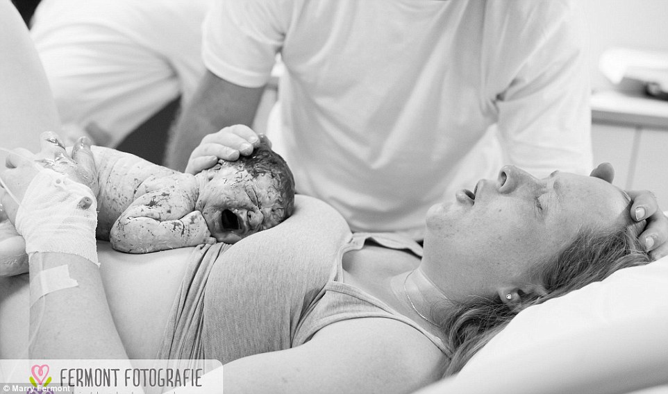 Still exhausted from giving birth, a new mother has skin to skin time with her cryiny newborn as her partner supportively strokes her hair. Marry says that it