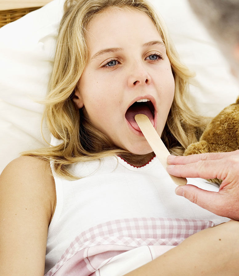 girl-tongue-depressor.jpg close-up of a male doctor putting a tongue depressor into a girl
